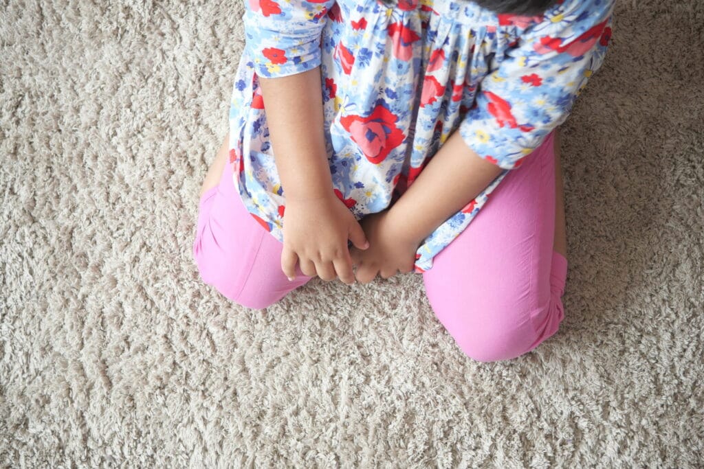 child-sits-on-beige-carpet-floor